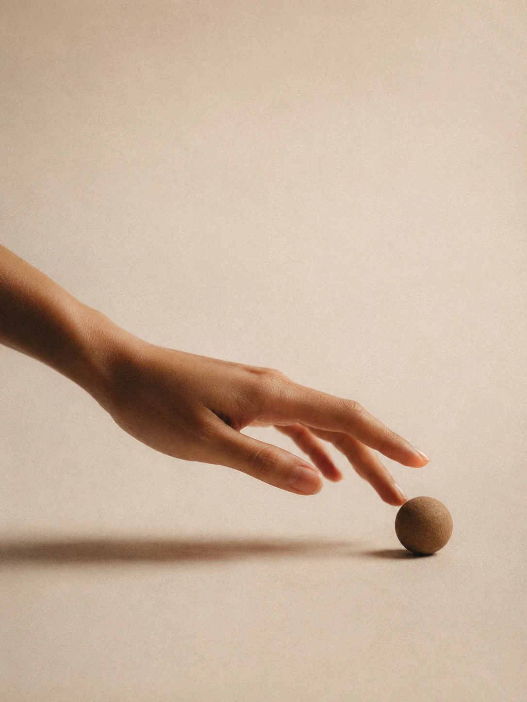 A hand steadying a wooden ball